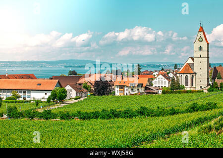 Panoramablick auf den Bodensee. Zeppelin, Apfelbäume und die Katholische Kirche St. Johann Baptist in Hagnau am Bild. Stockfoto