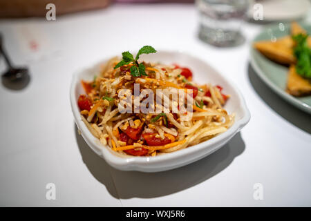Taichung, Taiwan: Thai Stil Papaya Salat mit frischen Tomaten und Erdnüssen und Minze Richtfest am weißen Tisch im Restaurant Stockfoto