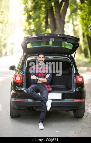 Junge Mann in ihrem Kofferraum sitzen auf der Straße Stockfoto