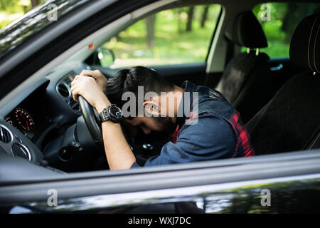 Closeup Portrait müde schönen jungen Mann mit kurzen Aufmerksamkeitsspanne, mit seinem Auto nach langen Stunden Reise, am Steuer, wach zu bleiben versuchen Ou isoliert Stockfoto