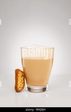 kleinen Cappuccino in einer Glasschale mit einem Cantuccini Cookie auf grauem Hintergrund Stockfoto