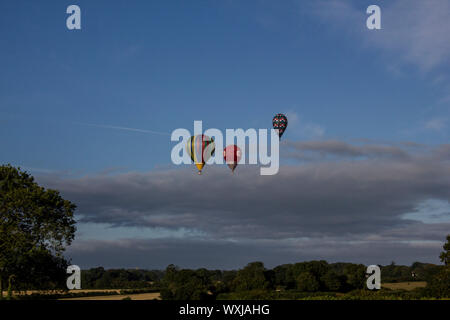 Drei Heißluftballons über die englische Landschaft fliegen mit ein paar Wolken hinter Ihnen. Stockfoto