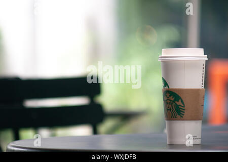 Bangkok, Thailand - Sep 1, 2019: eine große Tasse Starbucks Kaffee auf dem Tisch im Freien. Starbucks nehmen Kaffeetasse mit Logo, bokeh Innenraum backgrou Stockfoto