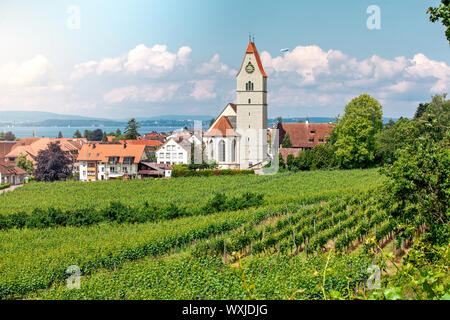 Panoramablick auf den Bodensee. Zeppelin, Apfelbäume und die Katholische Kirche St. Johann Baptist in Hagnau am Bild. Stockfoto