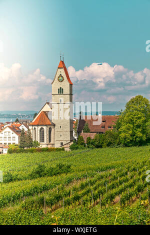 Panoramablick auf den Bodensee. Zeppelin, Apfelbäume und die Katholische Kirche St. Johann Baptist in Hagnau am Bild. Stockfoto