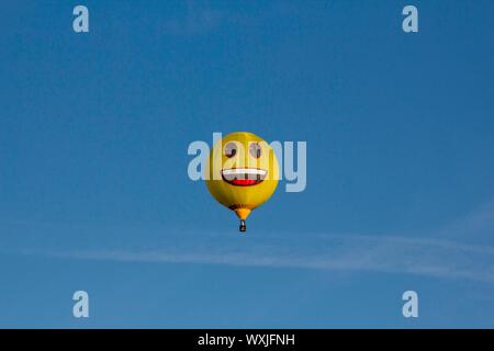 Eine gelbe glücklich emoji Heißluftballon vor blauem Himmel fliegen. Smiley Stockfoto