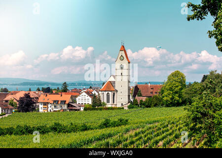 Panoramablick auf den Bodensee. Zeppelin, Apfelbäume und die Katholische Kirche St. Johann Baptist in Hagnau am Bild. Stockfoto