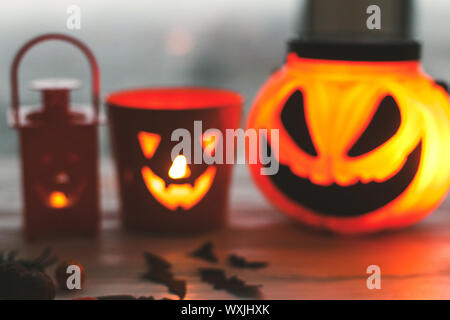 Verschwommenes Bild von glühenden jack o lantern Face, festliche Candy, Schädel, schwarz Fledermäuse, Geist, Spinne, Dekorationen auf weißem Hintergrund in dunklem Holz. Happy H Stockfoto