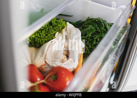 Frisches Gemüse in geöffneten Schublade im Kühlschrank. Kunststoff sich Karotten, Tomaten, Champignons, Zwiebeln, Radieschen, Salat, Rucola aus Markt im Kühlschrank. Null Stockfoto