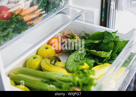 Vegetarische Ernährung. Kunststoff kostenlos Bananen, Salat, Spinat, Sellerie, Äpfel, orange im Kühlschrank. Null Abfall einkaufen. Frisches Gemüse in geöffneten Schublade Stockfoto