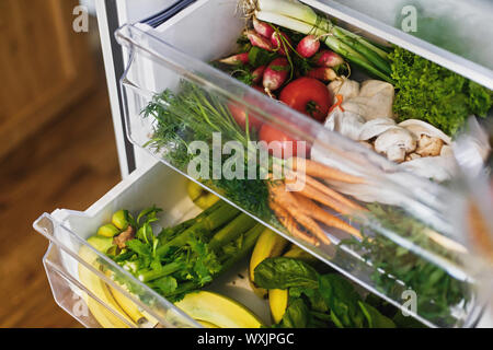 Null Abfall Lebensmittel im Kühlschrank. Frisches Gemüse in geöffneten Schublade im Kühlschrank. Kunststoff sich Karotten, Tomaten, Pilze, Bananen, Salat, Sellerie, Apple Stockfoto