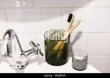 Kunststoff frei. Eco Natural bamboo Zahnbürsten in Glas und organische Holzkohle Zahnpasta in Glas Glas am Waschbecken im Badezimmer. Null Abfall bat Stockfoto