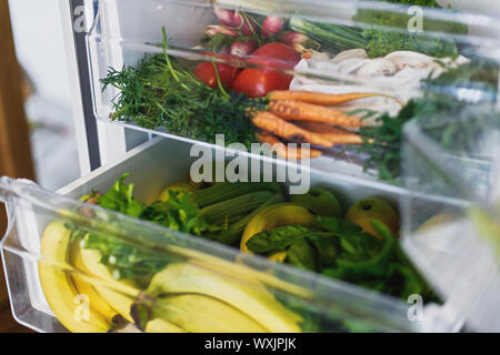 Null Abfall Lebensmittel im Kühlschrank. Frisches Gemüse in geöffneten Schublade im Kühlschrank. Kunststoff sich Karotten, Tomaten, Pilze, Bananen, Salat, Sellerie, Apple Stockfoto