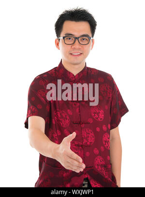 Asiatischer Mann in traditionellen Chinesisch Cheongsam oder Tang Anzug, die Hand ausstrecken, einen Händedruck, Stand isolierten auf weißen Hintergrund zu geben. Asiatische Männermodel. Stockfoto