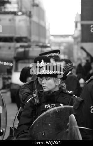 Die Polizei, die in der Linie der Aufgabe bei einer Demonstration in London, UK. Gefährliche Berufe. Polizisten, die in der Linie der Brand in britischen Städten. Die dünne blaue Linie. Schwarz-weiß-Bild. Authentische Bildsprache. Die Gewalt der Polizei gewalttätige Angriffe auf die Polizei zu. Respekt vor der Polizei. Polizei unterfinanziert. Regierung unter Finanzierung. Sparmaßnahmen. Taser Waffen für Offiziere. Stockfoto