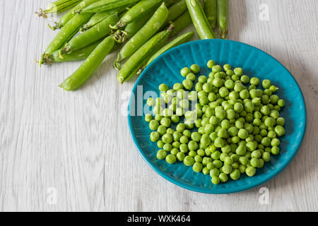 Garten Erbsen mit Hülsen auf einem blauen Schild. Graues Holz Hintergrund Stockfoto