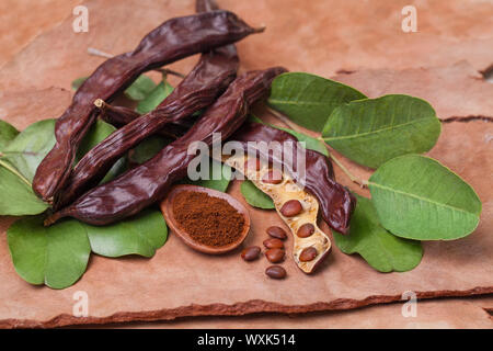 Johannisbrot. Bio Johannisbrot Schoten mit Samen und Blätter auf baumrinde Tabelle. Das gesunde Essen, essen Hintergrund. Stockfoto