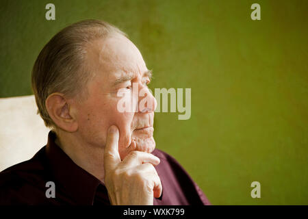 Älterer Mann im Schaukelstuhl aus sonnigen Fenster zu schauen Stockfoto