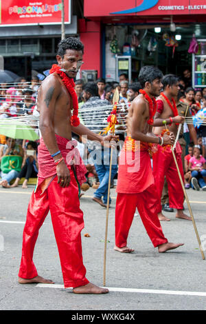 Hindu Kavadi Tänzer mit Piercings durch ihre Wangen und Haken durch den Rücken führen Sie entlang einer Straße in Kandy, Sri Lanka bei Tag Perahera. Stockfoto