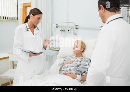 Männlichen und weiblichen Arzt stehen neben einem Patienten in einem Krankenhausbett Stockfoto