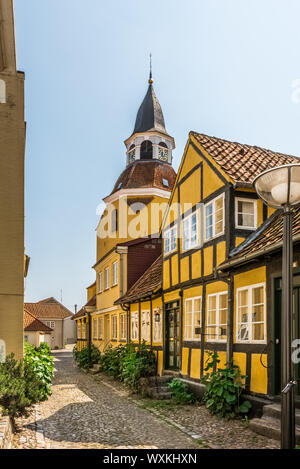 Der Glockenturm von Faaborg und ein Gelbes Fachwerkhaus am Ende der schmalen Gasse in Faaborg, Dänemark, 12. Juli 2019 Stockfoto