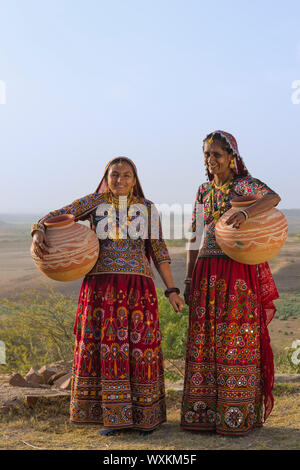 Zwei Ahir Frauen in traditionellen bunten Tuch mit Wasser in einem Tongefäß Kanne, tolle Rann von Kutch Wüste, Gujarat, Indien. Stockfoto