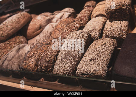 Viele verschiedene gesunde Brot mit mit Sonnenblumenkerne und Sesam auf einem Brot Regal in einem Lebensmittelgeschäft. Roggen frische Backwaren. Stockfoto