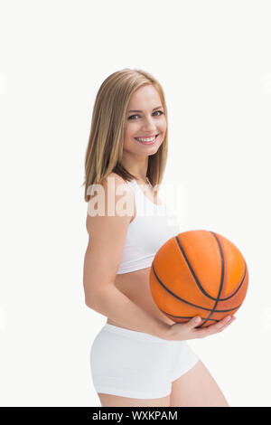 Porträt der glückliche Frau in Sportkleidung mit Basketball auf weißem Hintergrund Stockfoto