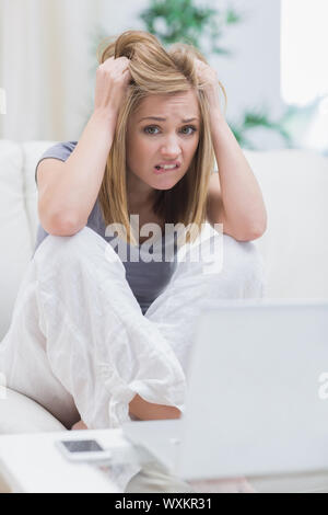 Porträt von frustrierten lässige junge Frau vor Laptop auf Couch zu Hause Stockfoto