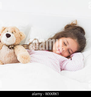 Kleines Mädchen im Bett schlafen mit Teddybär Stockfoto