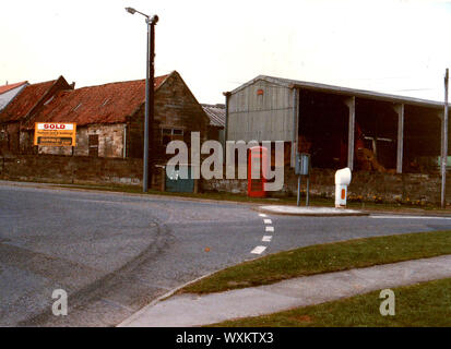 Juni 1986. Ehemaligen landwirtschaftlichen Gebäuden auf vier Fahrstreifen endet Kreisverkehr (Straße auf Serpentinen auf der rechten Seite), Whitby, Yorkshire, England, vor der Sanierung. Die Gegend am Rande der Stadt enthält jetzt Wohnimmobilien. Auf der Lamp Post können eine alte AIR RAID SIREN, gesehen werden und darunter eine traditionelle britische rote Telefonzelle. Stockfoto