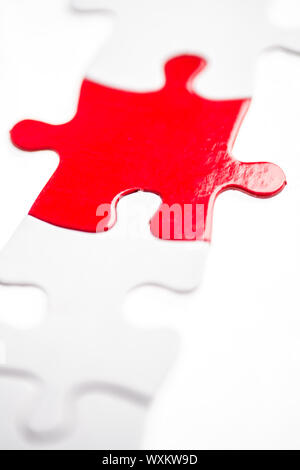 Red Puzzle Stück in einer Linie der weißen Stücke Stockfoto