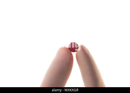 Behandschuhte Hand, die roten Tablette zwischen Daumen und Zeigefinger auf weißem Hintergrund Stockfoto
