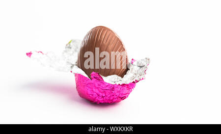 Osterei ausgepackt in rosa Folie auf weißem Hintergrund Stockfoto