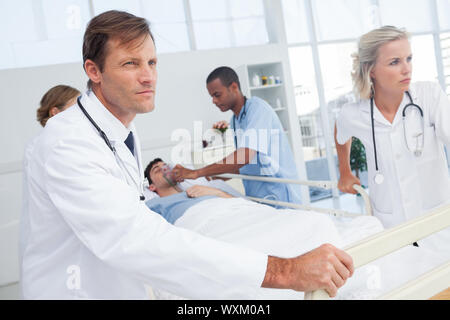 Ärzte drücken das Bett eines Patienten, während der Patient liegt auf im Notfall Stockfoto