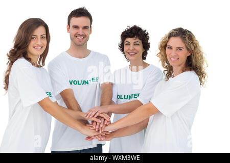 Lächelnd freiwillige Gruppe häufen ihre Hände auf weißem Hintergrund Stockfoto