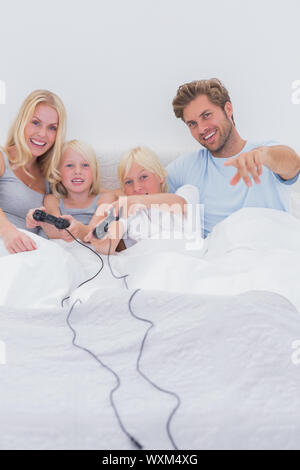 Fröhliche Familie spielen von Videospielen im Bett Stockfoto