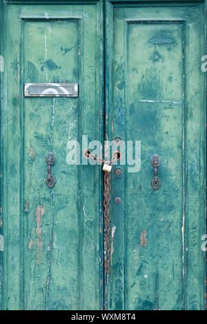 Alte verschlossene Tür mit abblätternde Farbe, Vorhängeschloss und Kette in Venedig, Italien Stockfoto