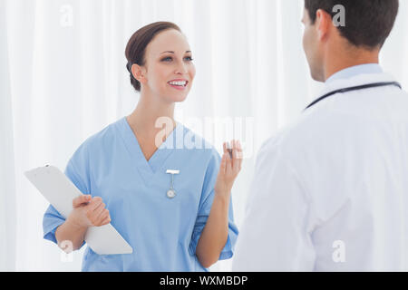 Fröhliche hübsche Chirurg und Arzt in hellen Büro miteinander reden Stockfoto