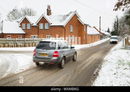 Autos fahren auf Schnee im Winter auf ländliche englische Straßen. Buckinghamshire, England, Großbritannien Stockfoto