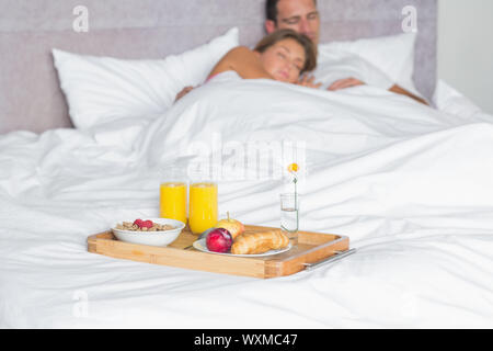 Paar mit Frühstückstablett auf Bett zu Hause schlief im Schlafzimmer kuscheln Stockfoto