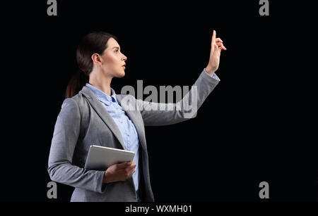 Business Girl Holding Tablet Drücken der Taste Auf unsichtbaren Touchscreen, Studio Stockfoto