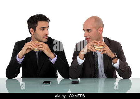 Duo von Geschäftsleuten, die Hamburger Essen Stockfoto