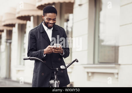 Unternehmer im Chat am Telefon, mit dem Fahrrad zur Arbeit Stockfoto