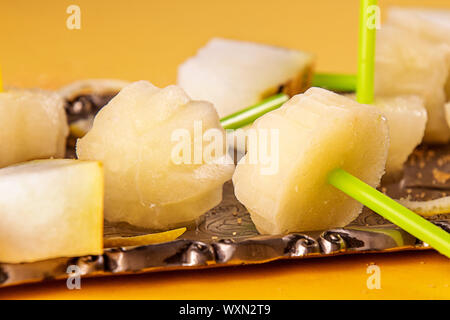 Hausgemachte Melone orange fruit Sorbet Granita Eis am Stiel am Stiel und Scheiben frische reife Melone Frucht auf Fach auf gelb blau Hintergrund. Sommer desse Stockfoto