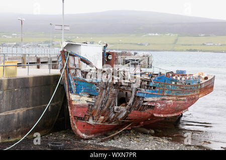 Ein Fischerboot weg Verrottung durch den Hafen am Pier der Wyre, Orkney Islands, gegenüber der Insel Rousay Stockfoto