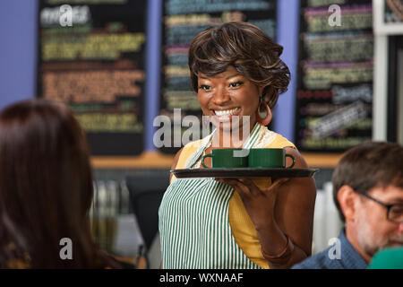 Schöne schwarze Frau in Schürze Getränke auf einem Tablett serviert Stockfoto