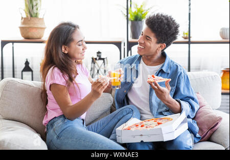 Gerne afrikanische Paar essen Pizza und Getränke zu Hause Stockfoto