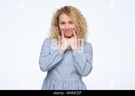 Mädchen versucht, so zu tun, als sie vor den Menschen glücklich ist. Negativen Gesichts menschliches Gefühl. Studio shot Stockfoto