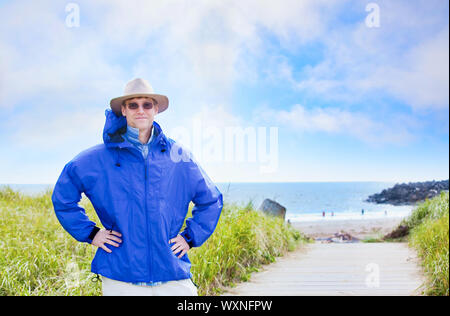 Hübscher kaukasischen Mann in den Vierzigern mit Regenjacke von Ocean shore Stockfoto